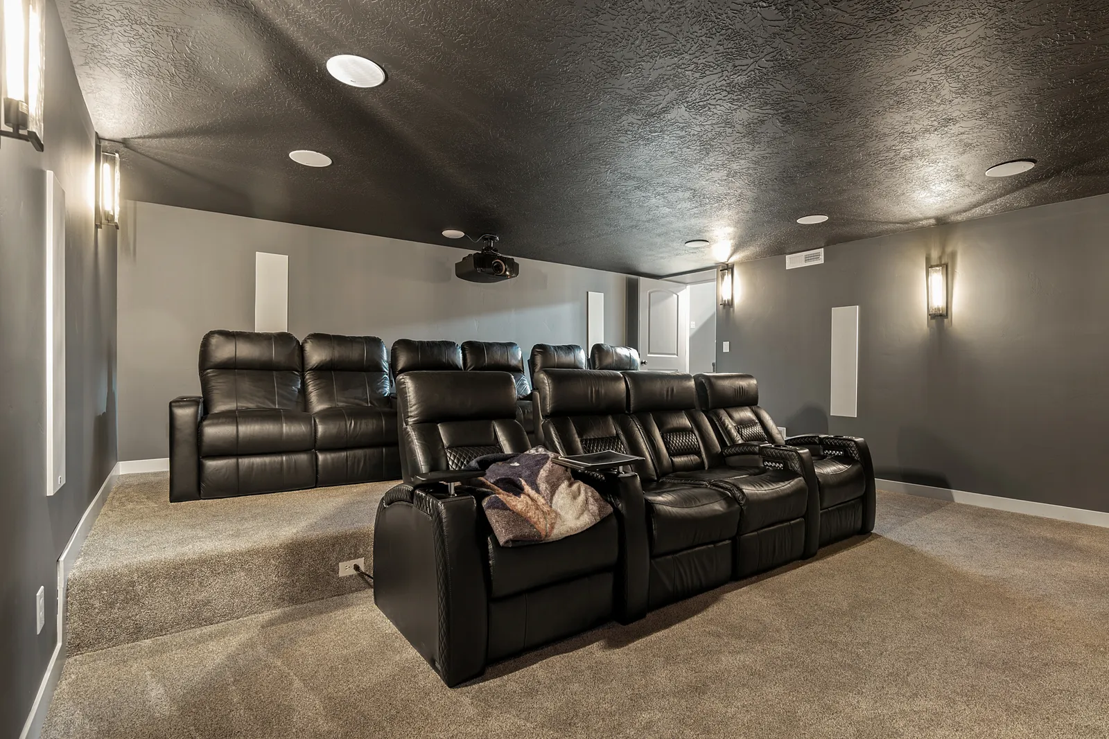 Finished basement home theater installed by our team — tiered leather seating, in-ceiling and in-wall speakers