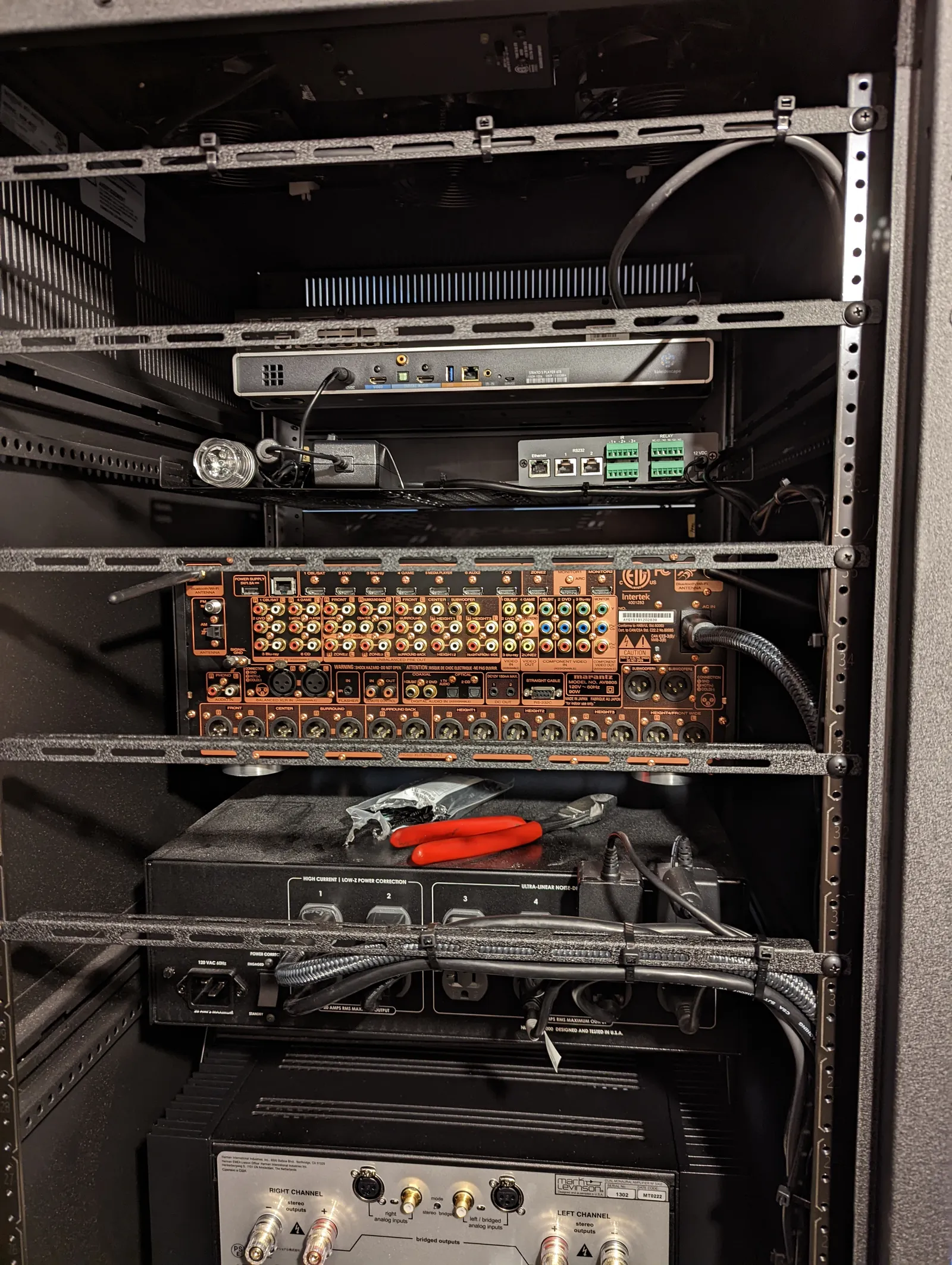 Equipment rack mid-install with movie server, processor, power conditioning, and reference amplifier
