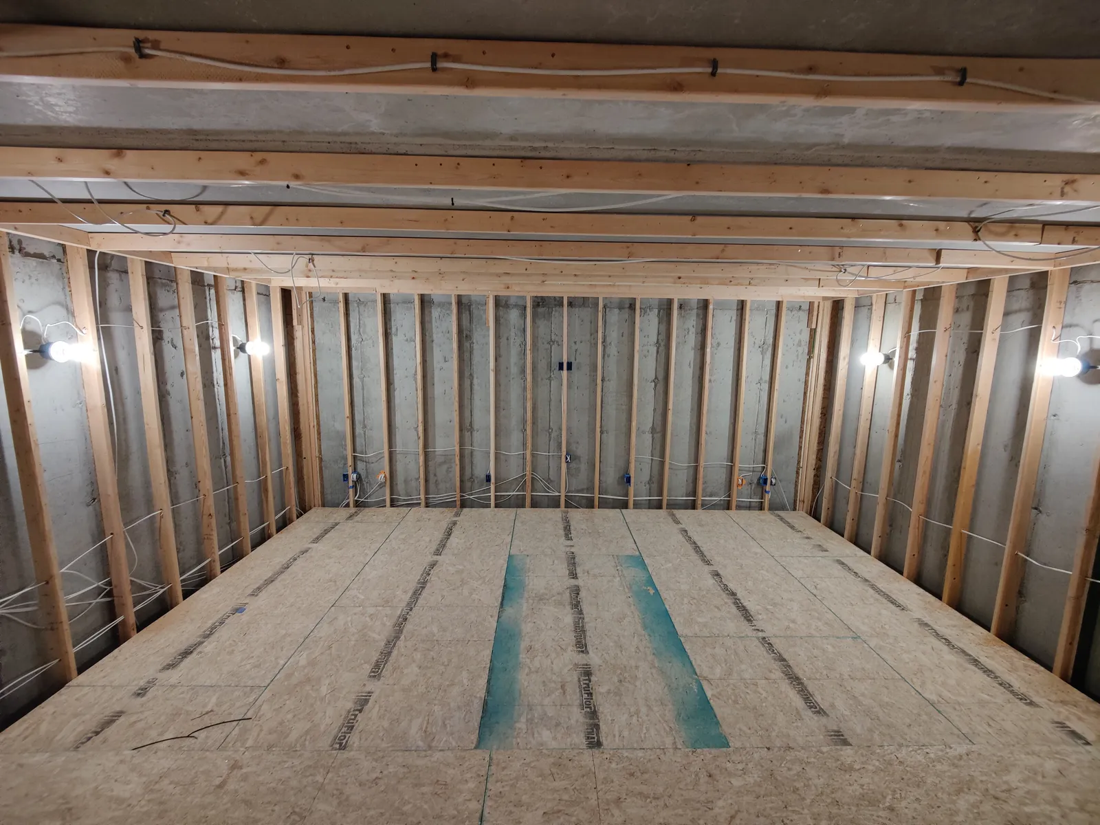 Framed basement room with riser platform built and low-voltage wiring run along the studs